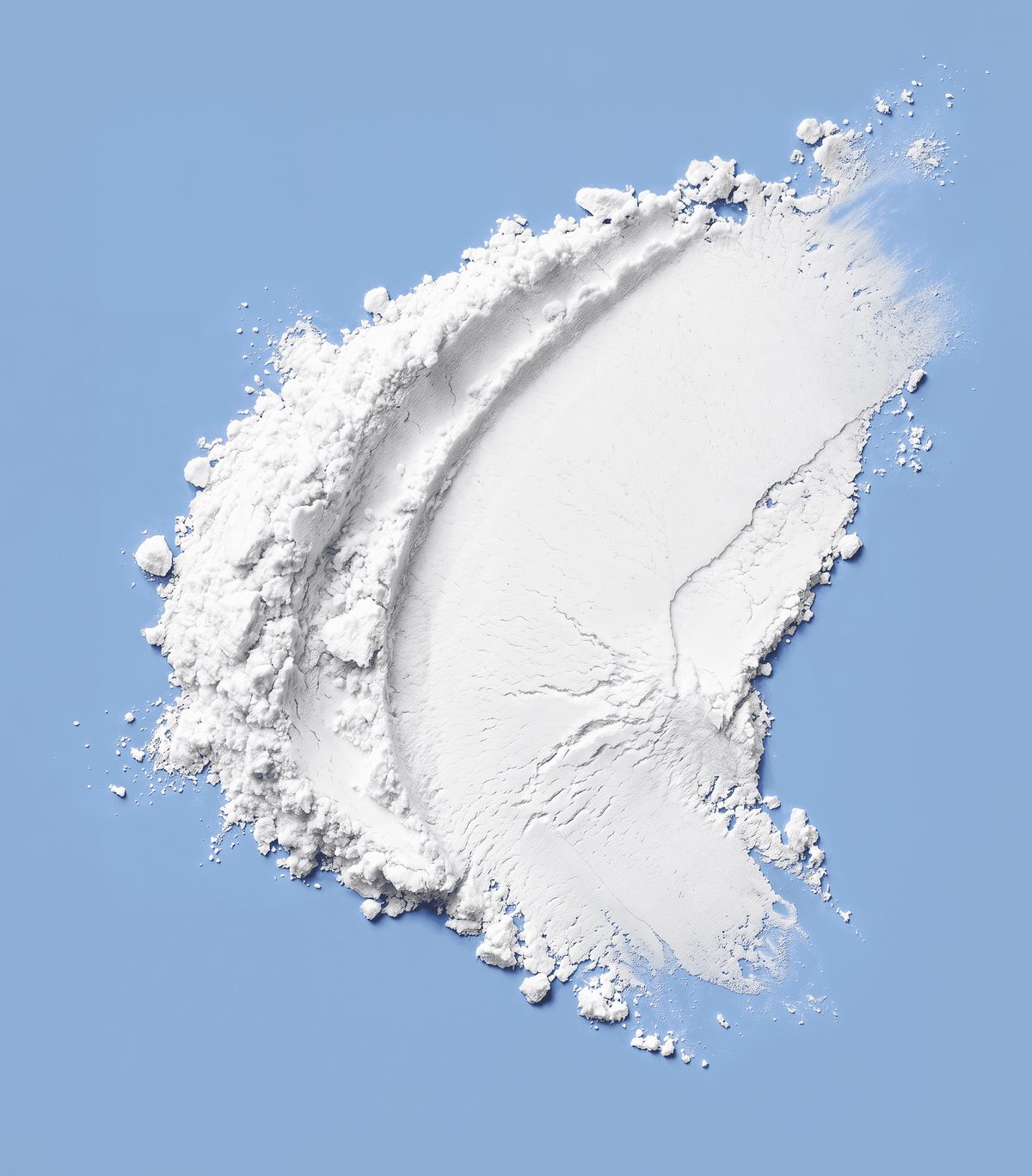 Micronised creatine monohydrate powder spread on a blue surface